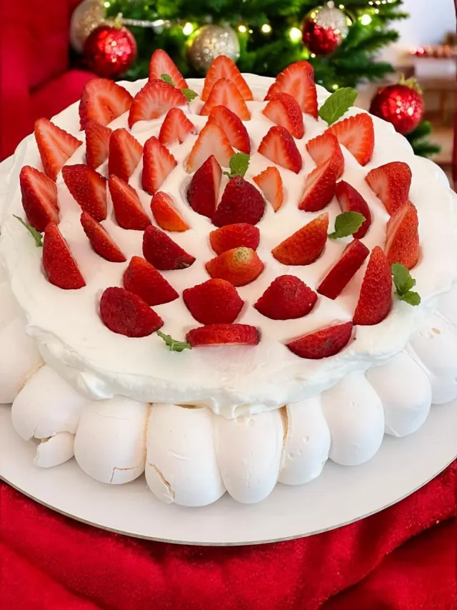 Pavlova com chantilly e morangos e decoração natalina ao fundo